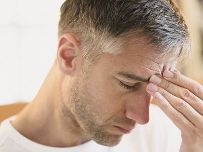 Close up of man with headache touching forehead