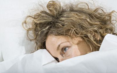 Woman in bed under white blanket