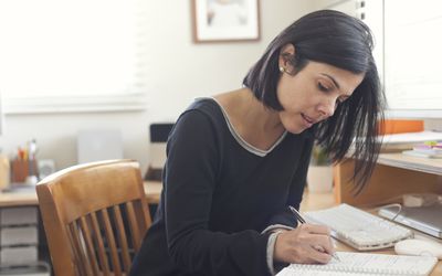 woman writing at home office desk