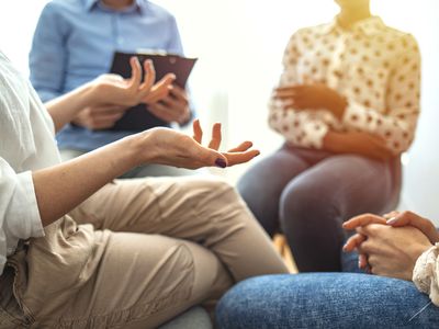 Woman gestures while discussing something difficult during a support group or group therapy session