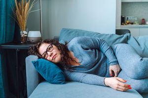 Woman lying on a couch holding her stomach.