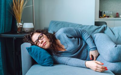 Woman lying on a couch holding her stomach.