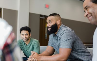 Three men smile during group therapy.