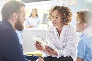 woman doctor with curly hair talking to male patient