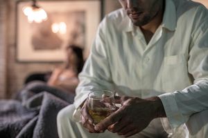 Man sitting on bed having a drink