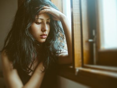 Sad young woman thinks near window