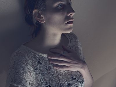 Scared woman leaning against a wall